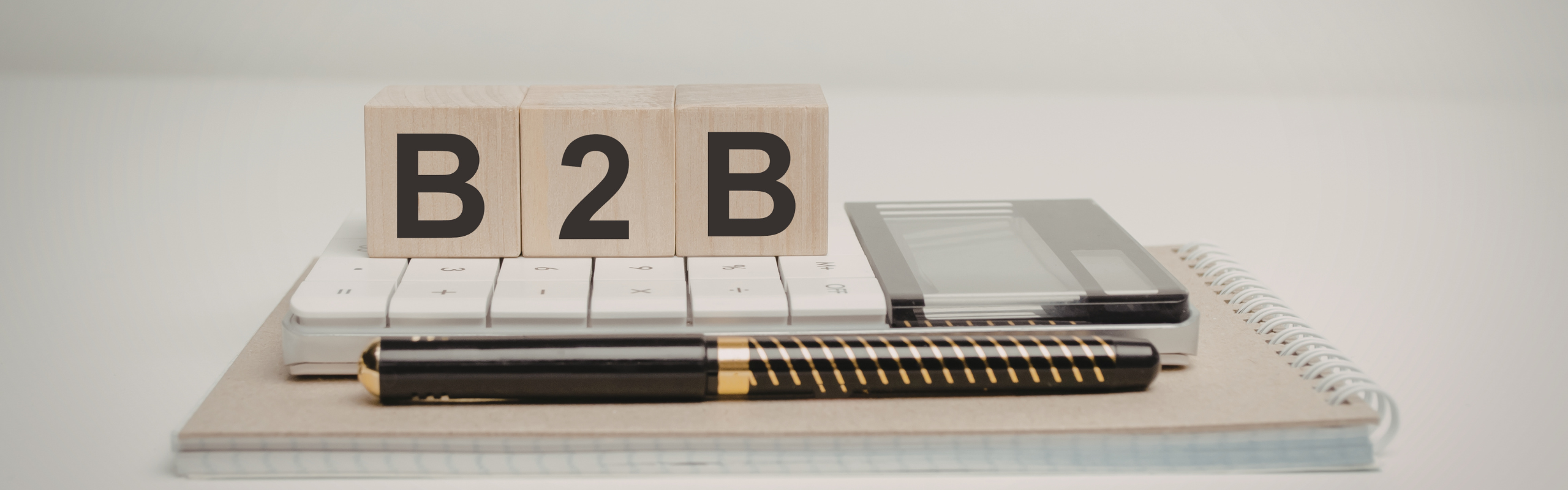 wooden cubes with word b2b - Business To Business and calculator, pen and notebook