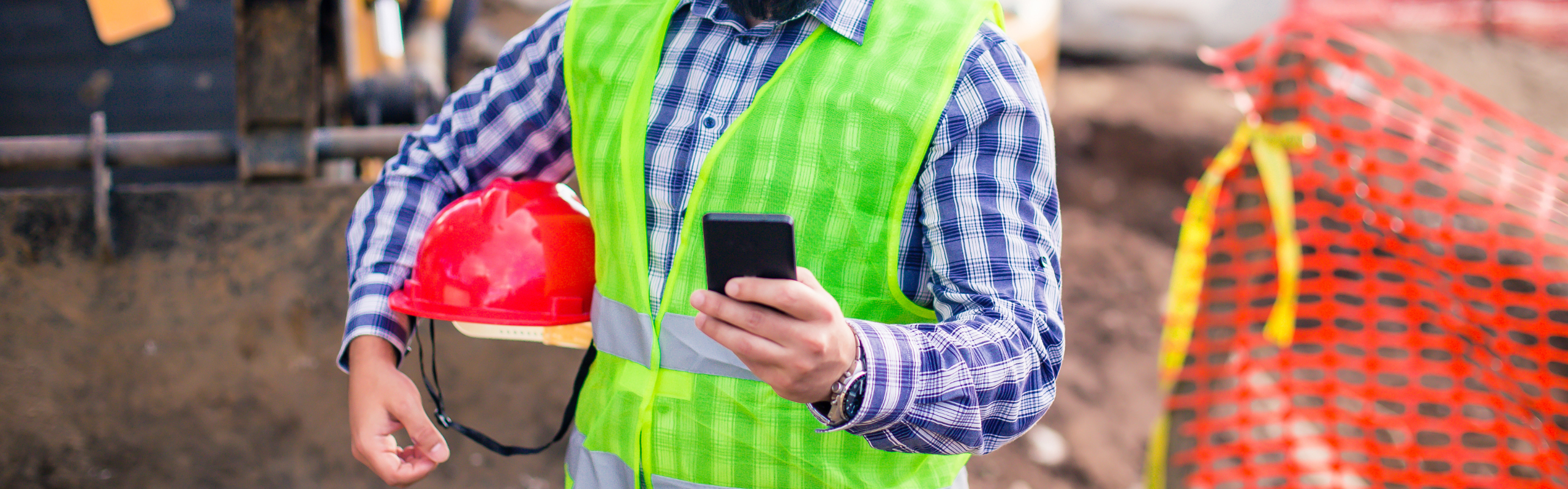 Construction worker checks cell phone.
