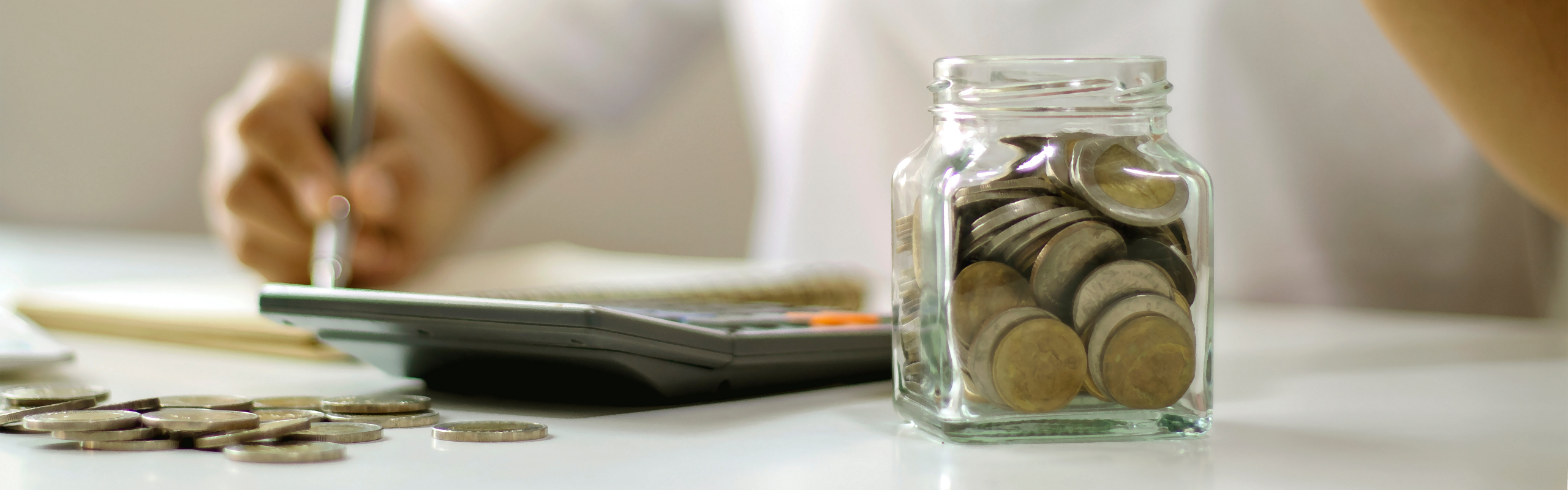 Person Depositing Coin Into a Jar of Coins