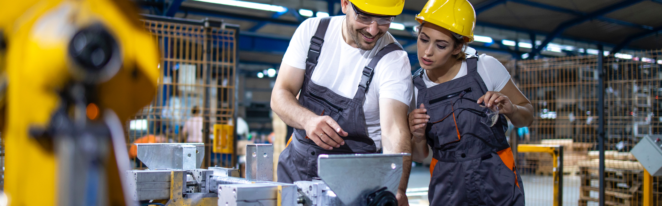 Factory worker training new employee to operate industrial machine.